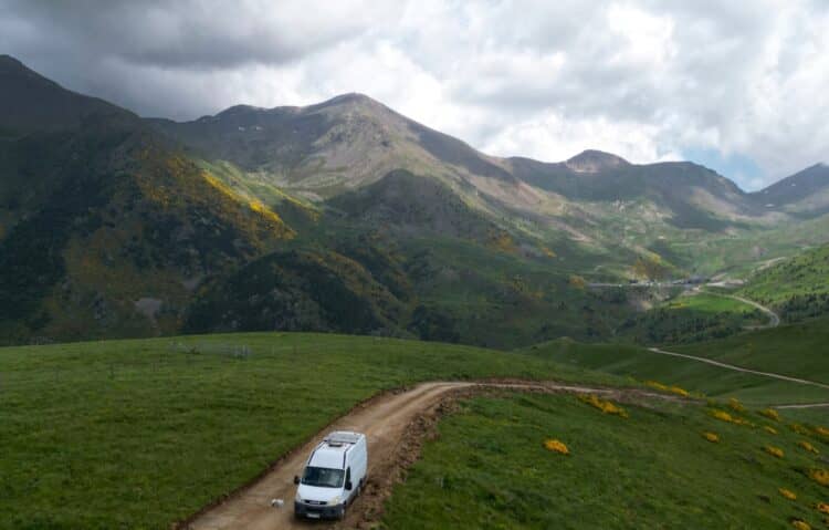 Camper van on a dirt track through green mountains